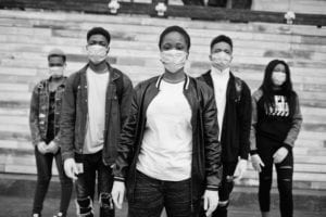 Group of masked young people standing and looking serious